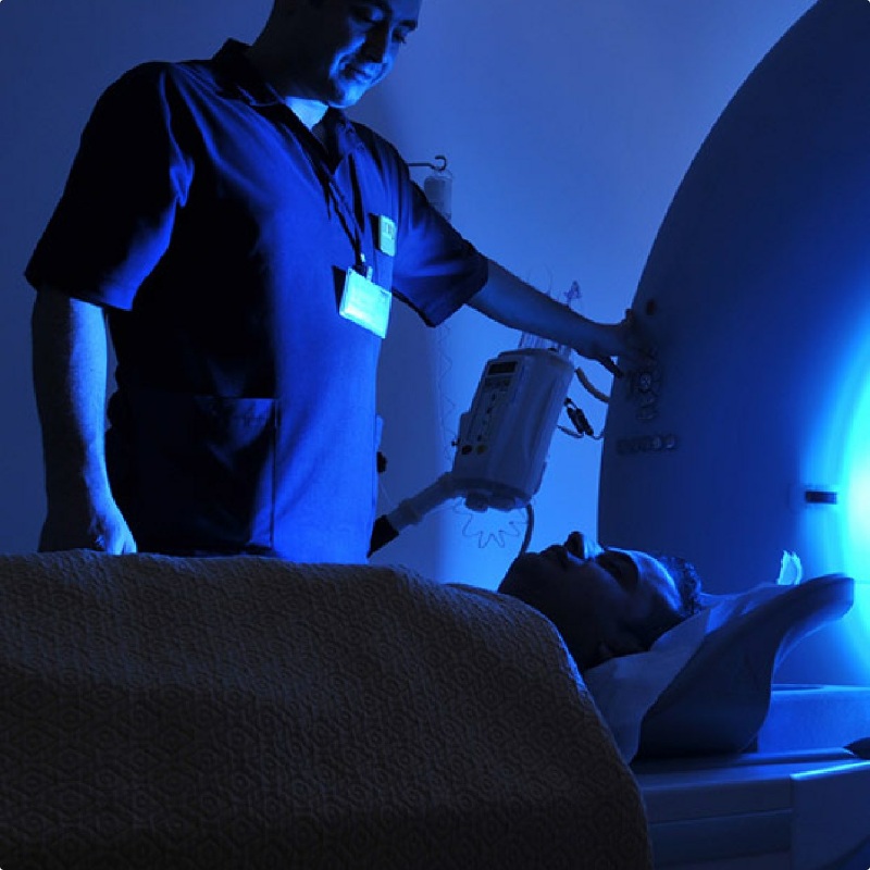 A photo of a tech helping a man into an MRI machine.